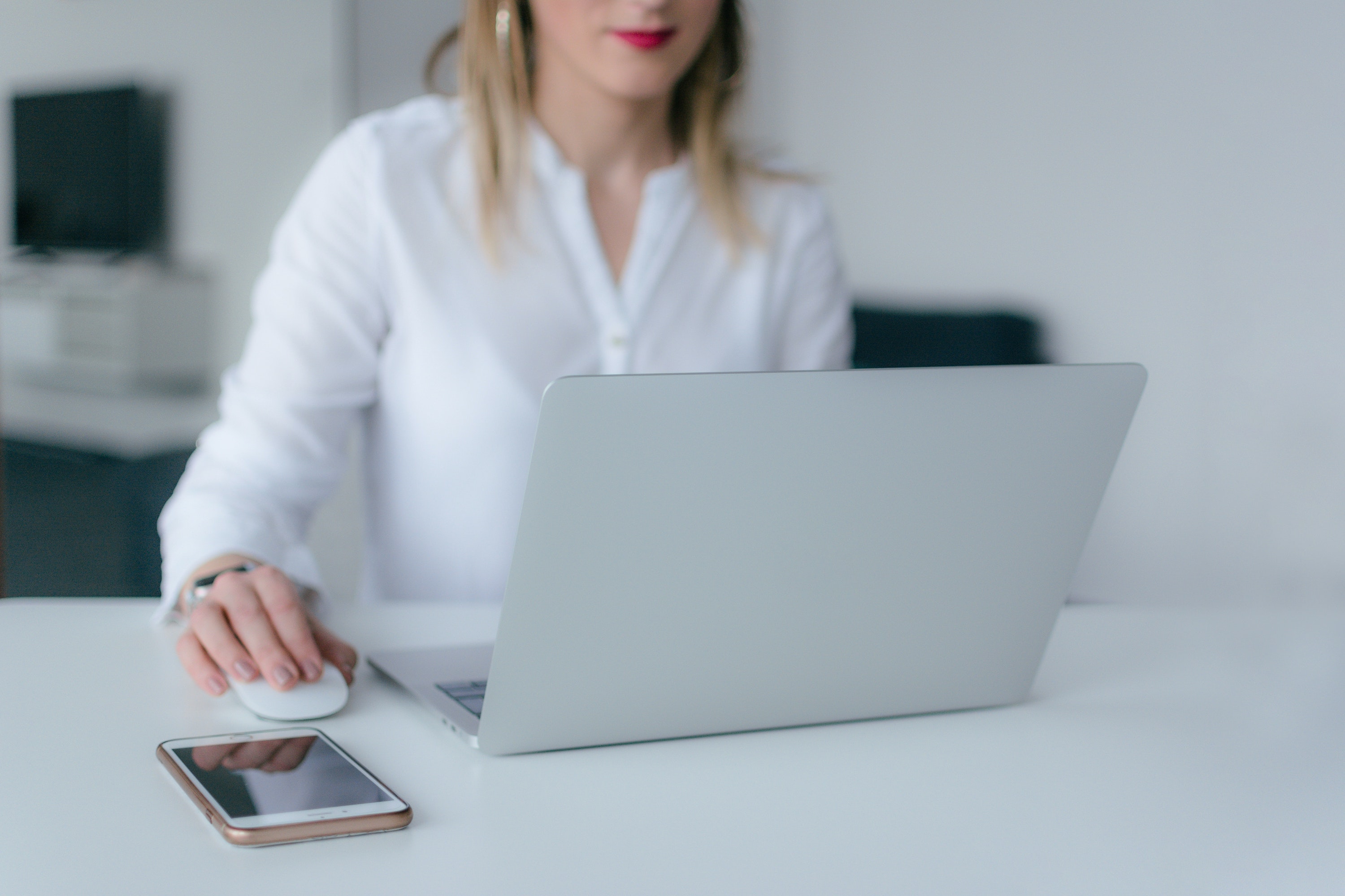 RP-CRO woman medical writer in white blouse sitting at a desk in front of an open laptop reviews clinical trial endpoints.